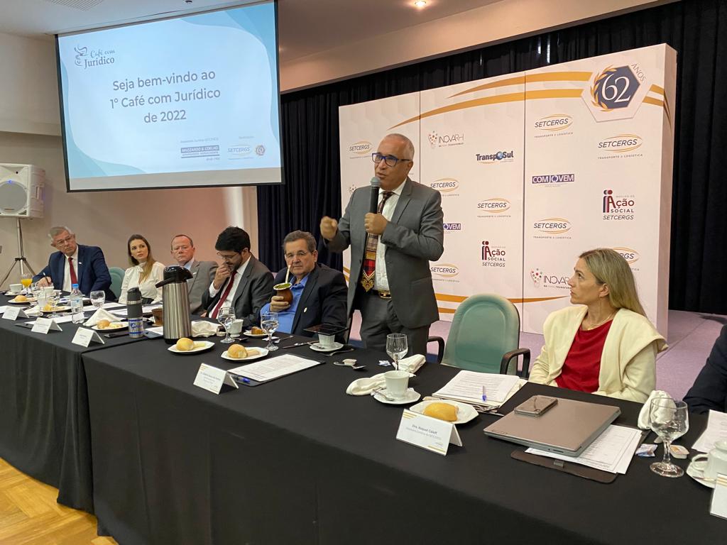 Foto do desembargador Gilberto Souza dos Santos, falando em pé, da mesa oficial.