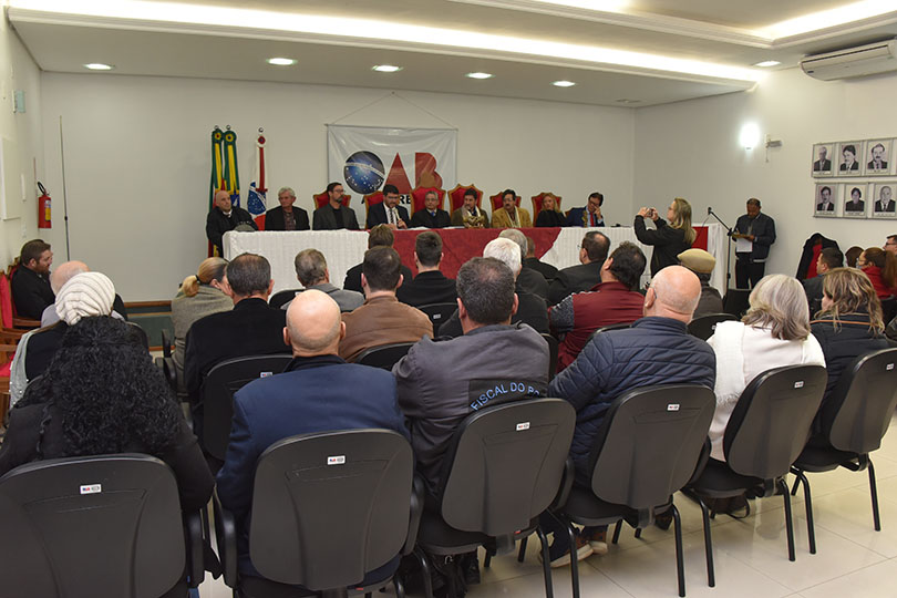 Foto da mesa oficial, com parte do público em primeiro plano