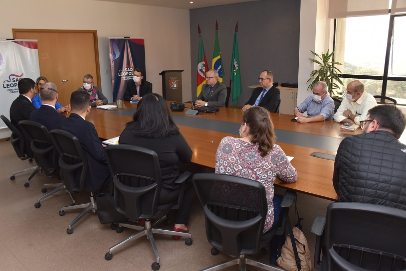 Foto em ângulo aberto da reunião, mostrando mesa e participantes