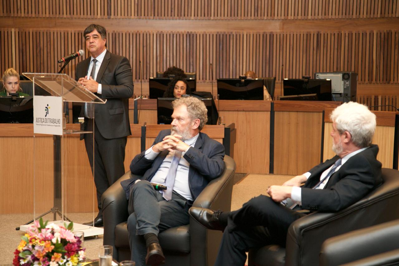 Foto tirada durante a exposição de Marthius Sávio Cavalcanti Lobato, com o painelista aparecendo ao fundo e parte do público em primeiro plano