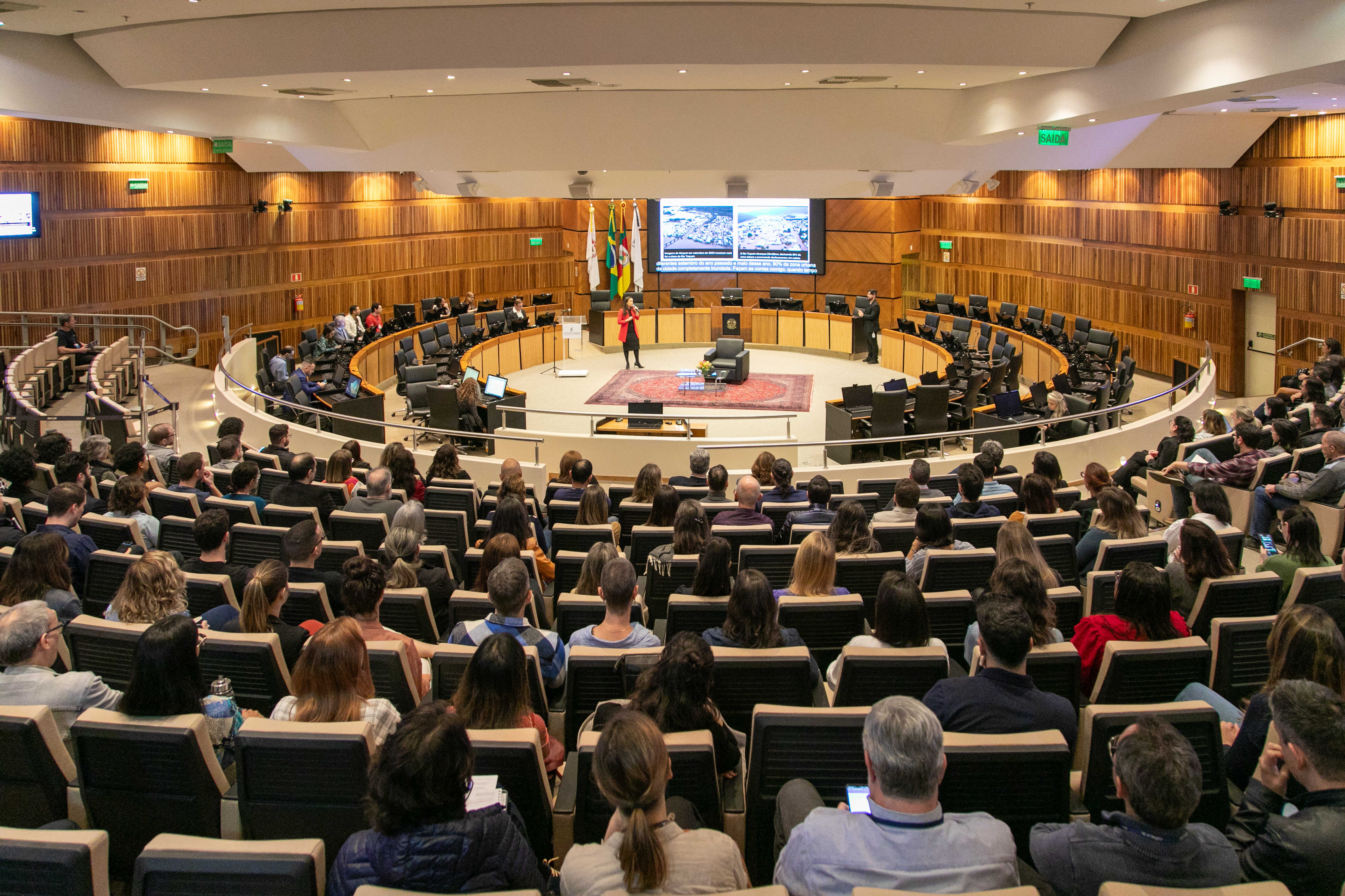 Púbico no plenário do TRT-RS. Ao fundo aparece a palestrante na nave central.