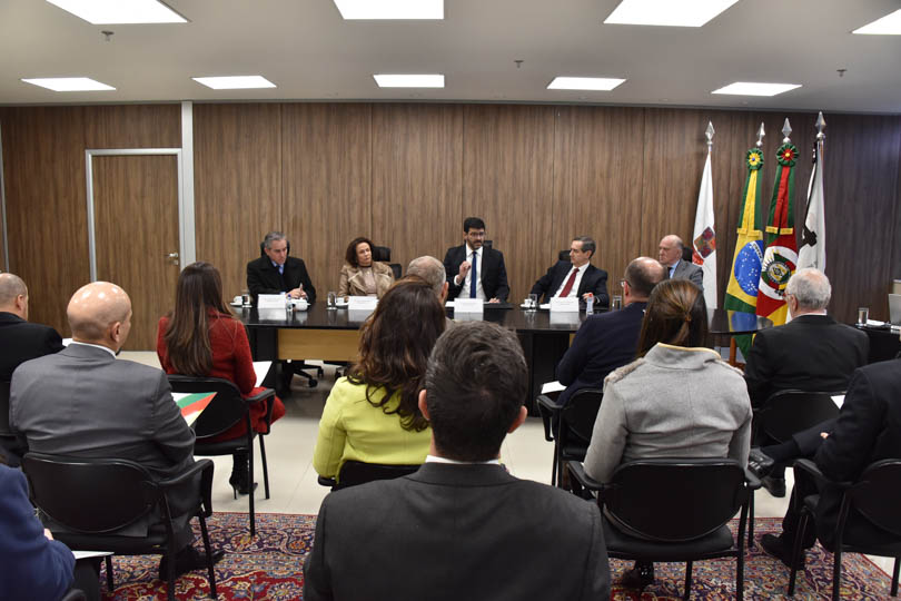 foto em ângulo aberto da reunião, mostrando mesa oficial e parte do público