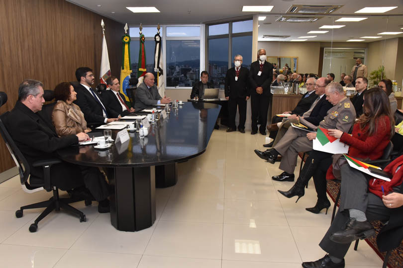 foto em ângulo aberto da reunião, mostrando mesa oficial e parte do público