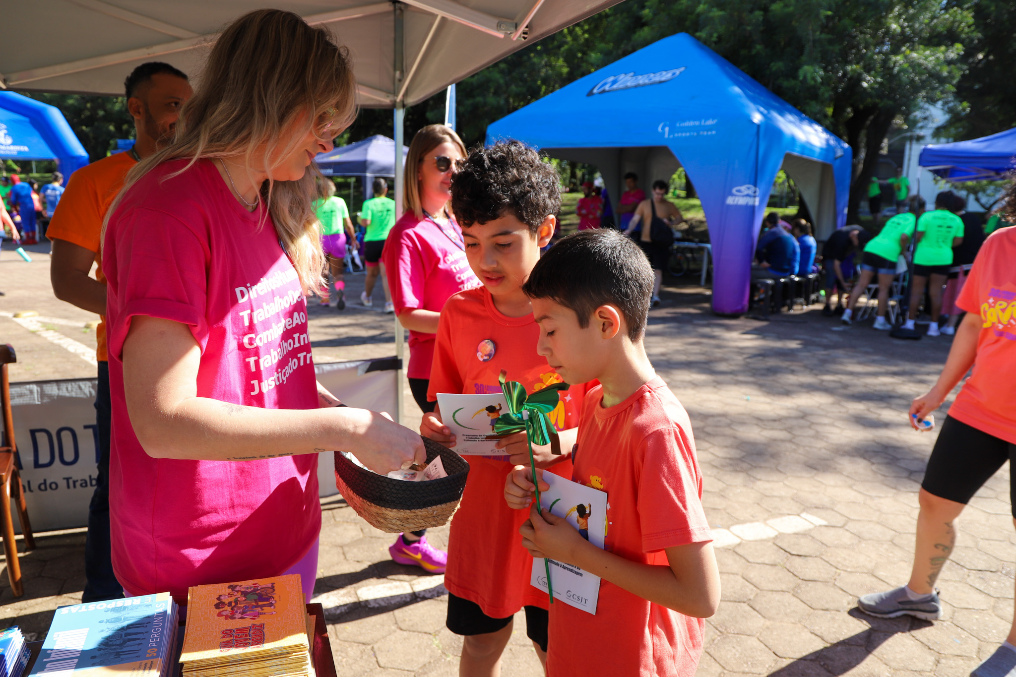 Servidora entrega tatuagens a crianças no estande do TRT-RS na maratona