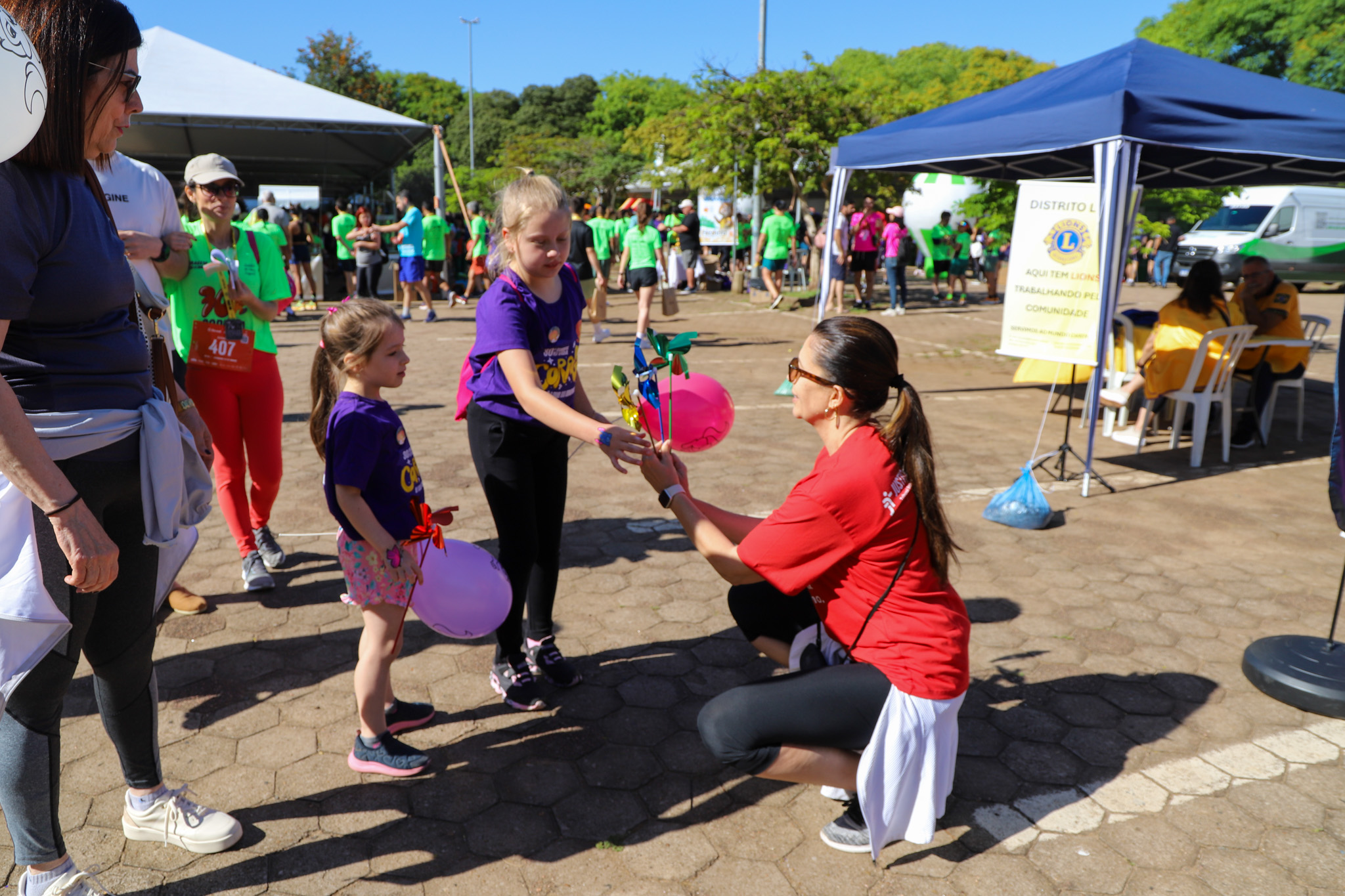 Juíza Aline entrega catavento a criança no estante do TRT-RS na Maratona