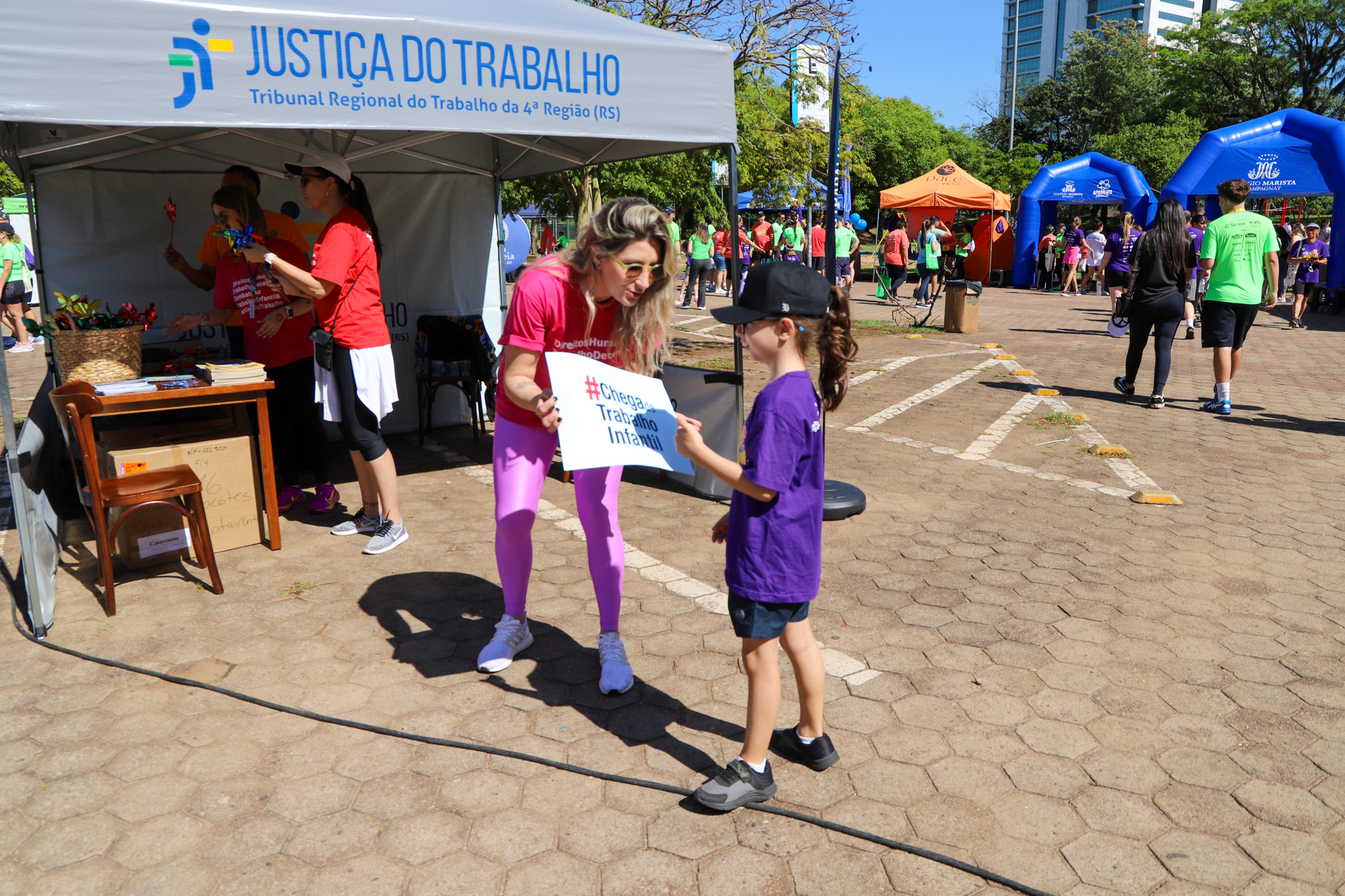 Servidora do TRT-RS entrega o cartaz #chega de trabalho infantil para criança maratonista