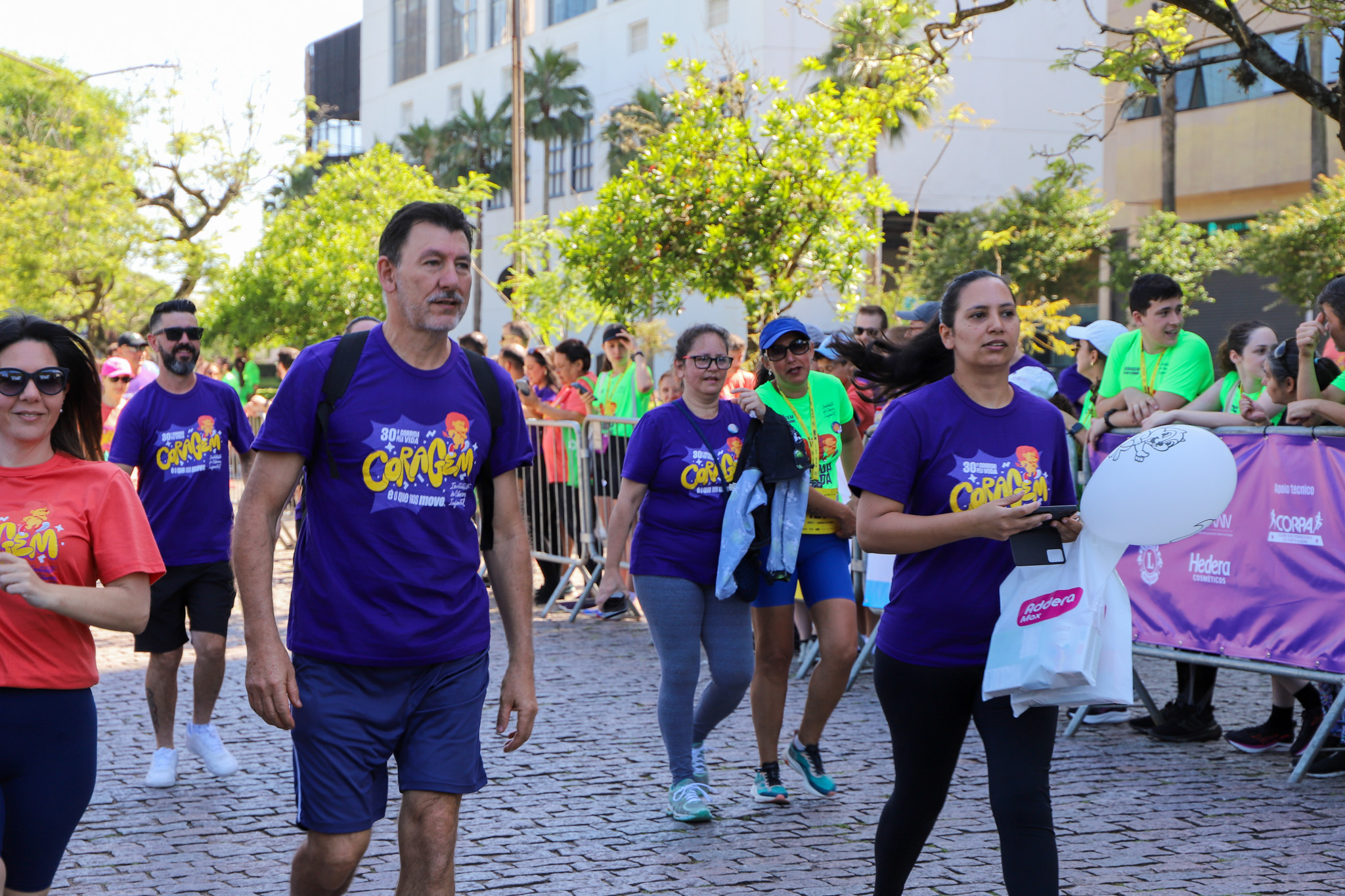 Homens e mulheres caminhando até o Pórtico de chegada da Maratona.