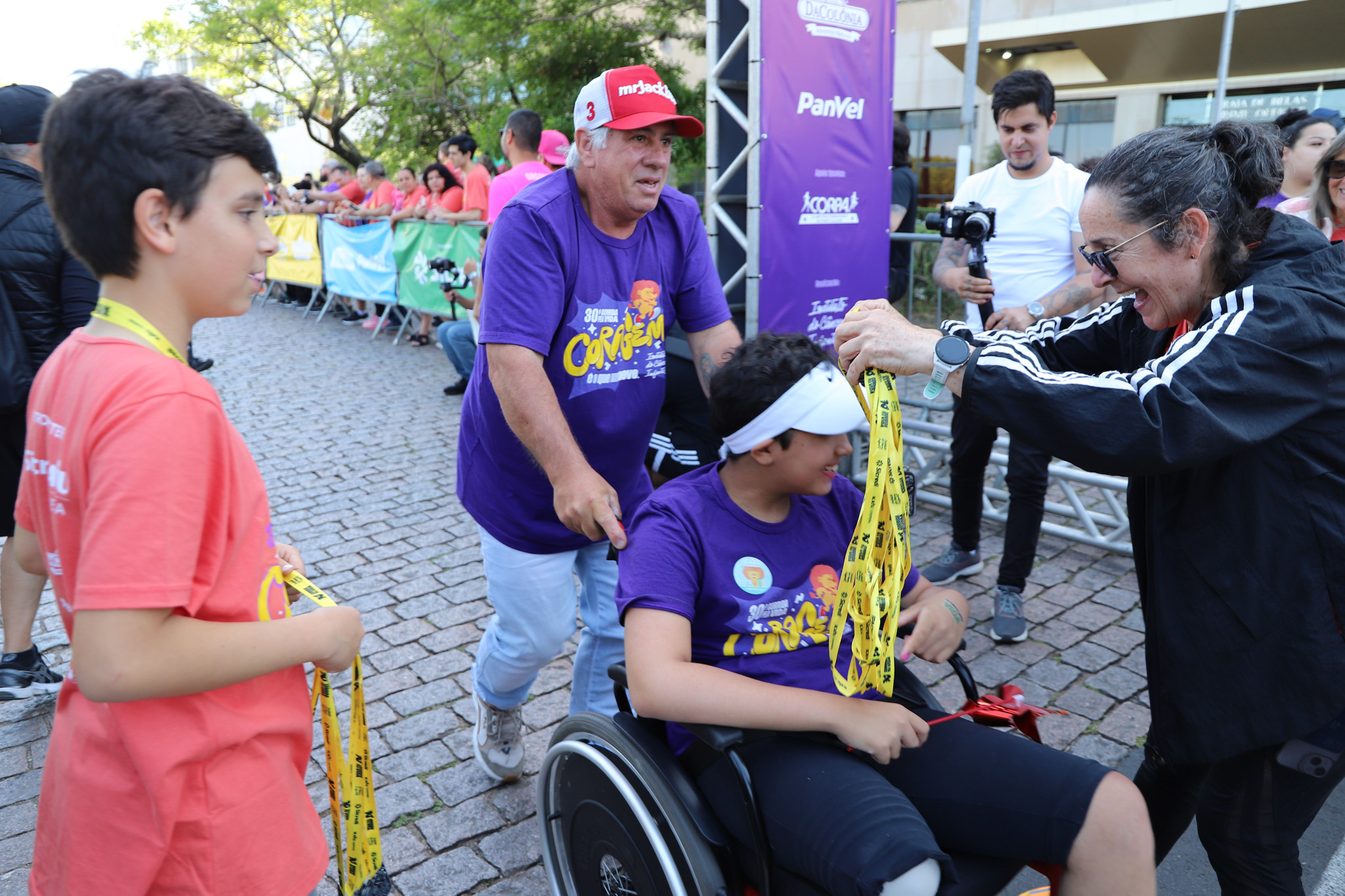 Participante em cadeira de rodas recebe medalha na corrida infantojuvenil.