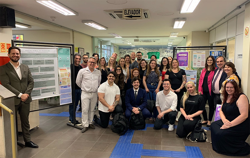 Participantes da solenidade posam para foto ao lado dos cartazes