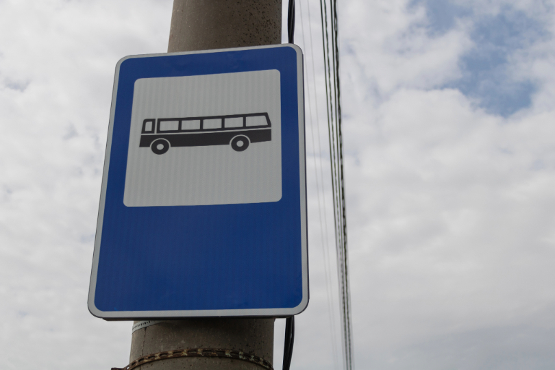Placa que indica parada de ônibus fixada em um poste. Desenho de ônibus na cor preta sobre fundo branco em moldura azul.