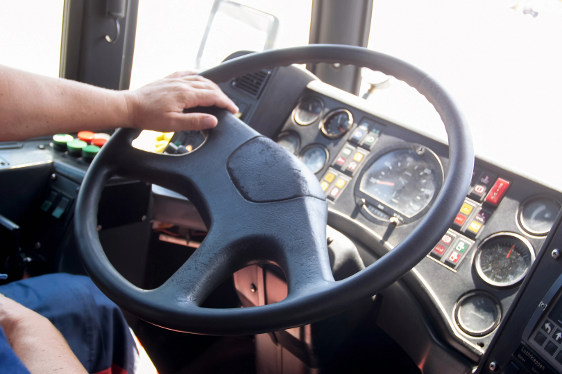 Mãos masculinas sobre direção de ônibus