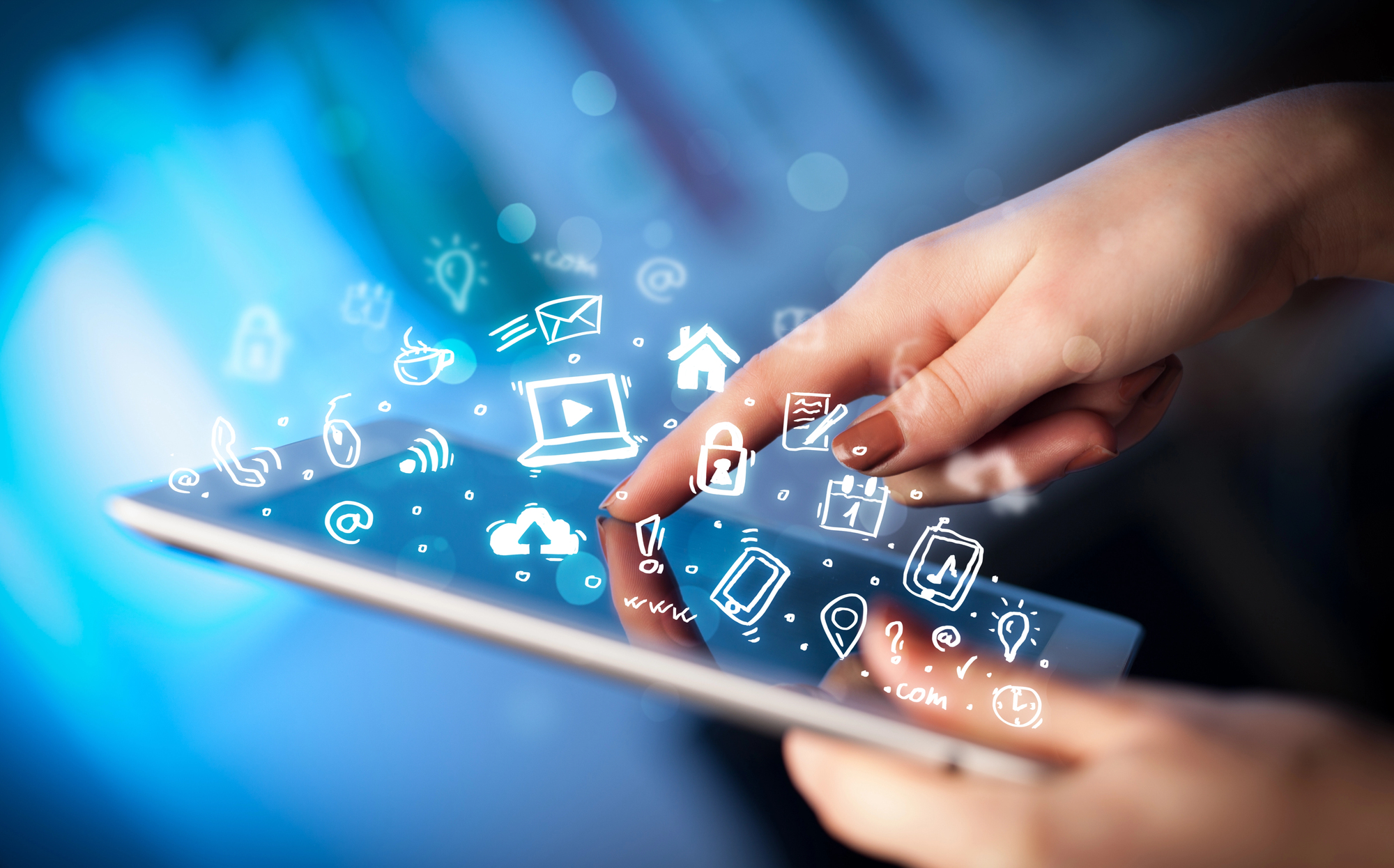 A imagem mostra uma mão interagindo com um tablet, com um fundo desfocado em tons de azul. Do dispositivo, surgem ícones digitais brilhantes desenhados em branco, representando funções como e-mail, Wi-Fi, segurança, localização e redes sociais. A cena transmite uma sensação de tecnologia avançada e conectividade digital.