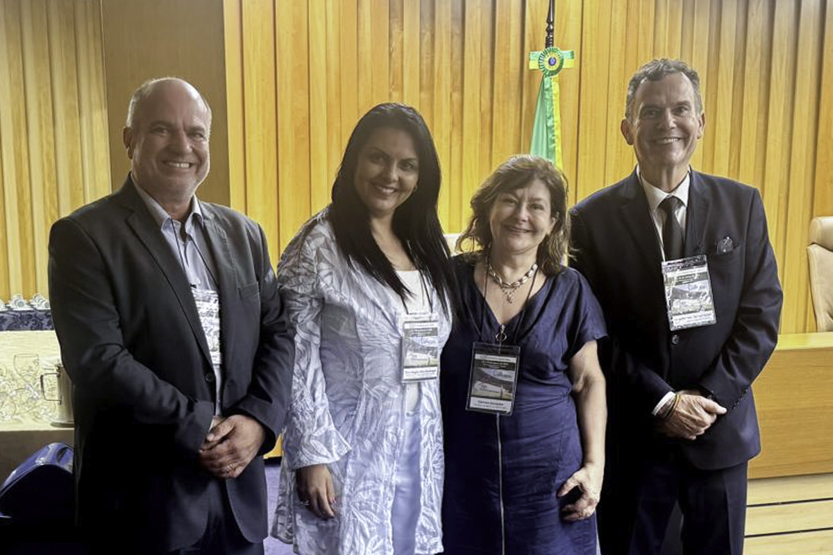 Foto posada dos desembargadores e desembargadoras no auditório do TST. Todos estão sorrindo. Ao fundo aparece uma parede de madeira e a bandeira do Brasil.