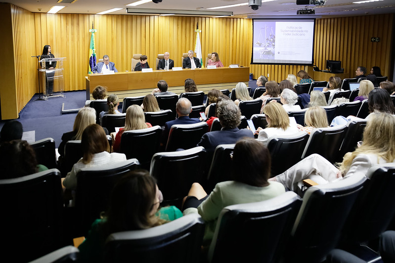 Auditório do TST, com público sentado de costas em primeiro plano e mesa oficial do evento ao fundo.