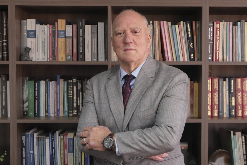 Des. Ricardo Martins Costa, em frente a uma estante de livros.