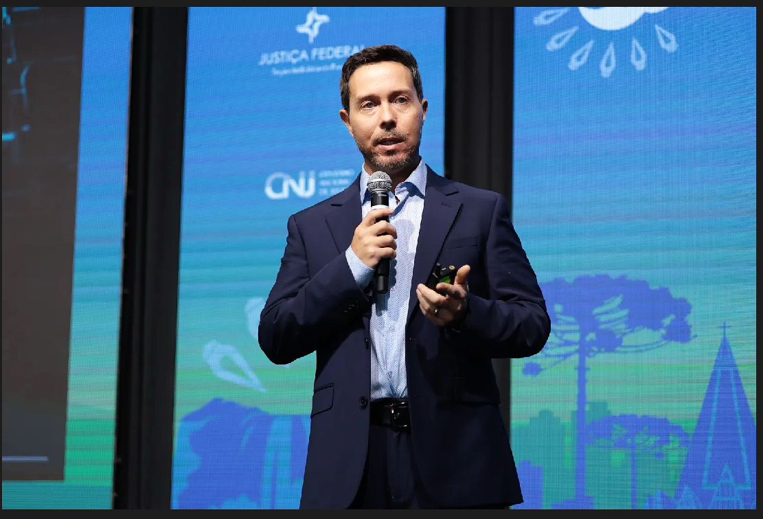 Foto do juiz Rodrigo fechada na apresentação no Festlabs com microfone na mão.