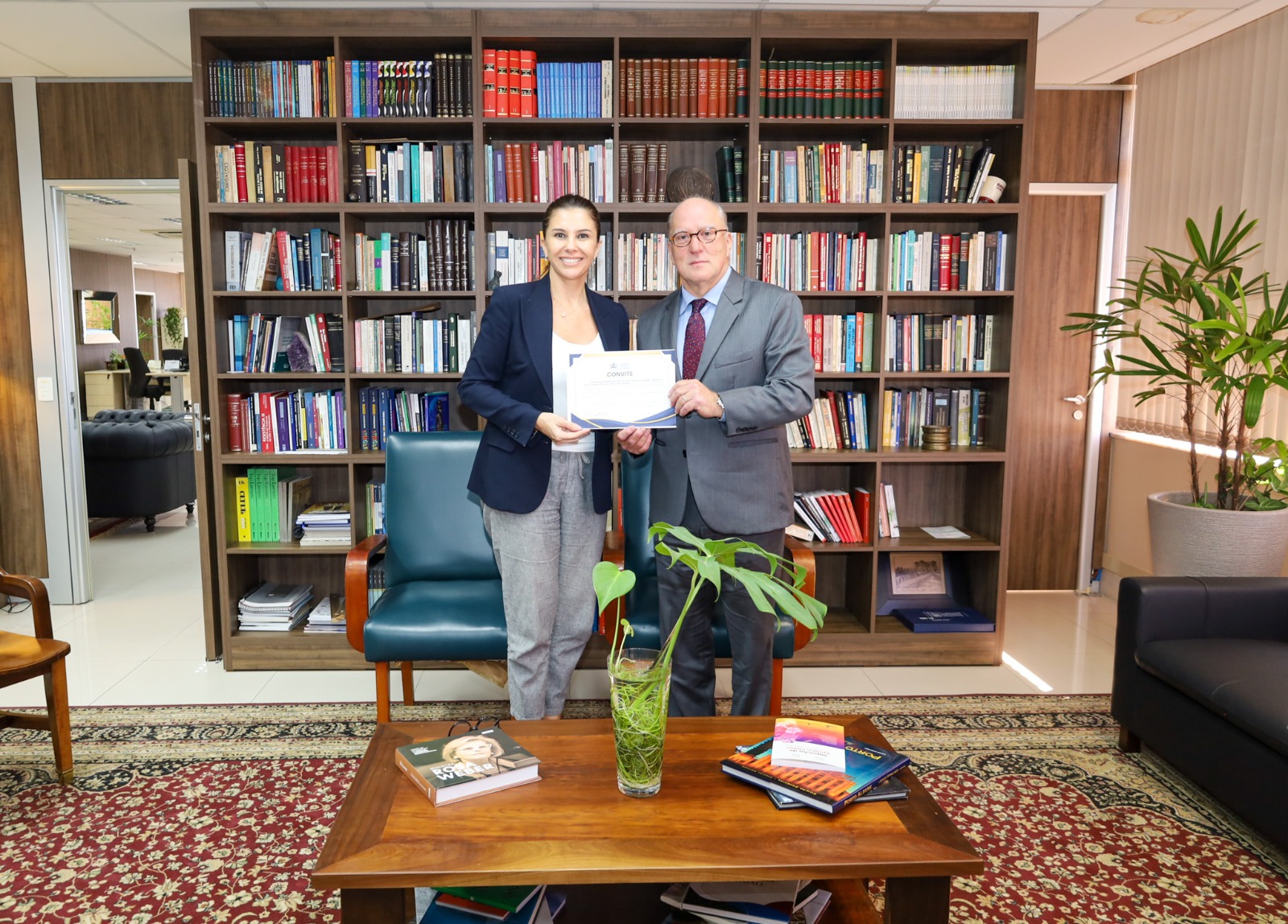 Foto posada do presidente Martins Costa recebendo convite da juíza Aline.
