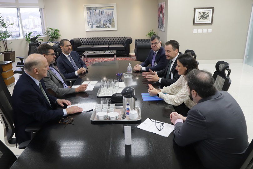Foto da reunião, mostrando os participantes sentados à mesa do Salão Nobre, conversando.