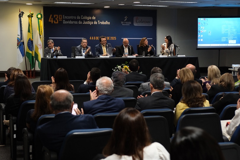 Foto da reunião, no auditório do TRT-RJ, mostrando mesa principal ao fundo e, em primeiro plano, o público de costas.