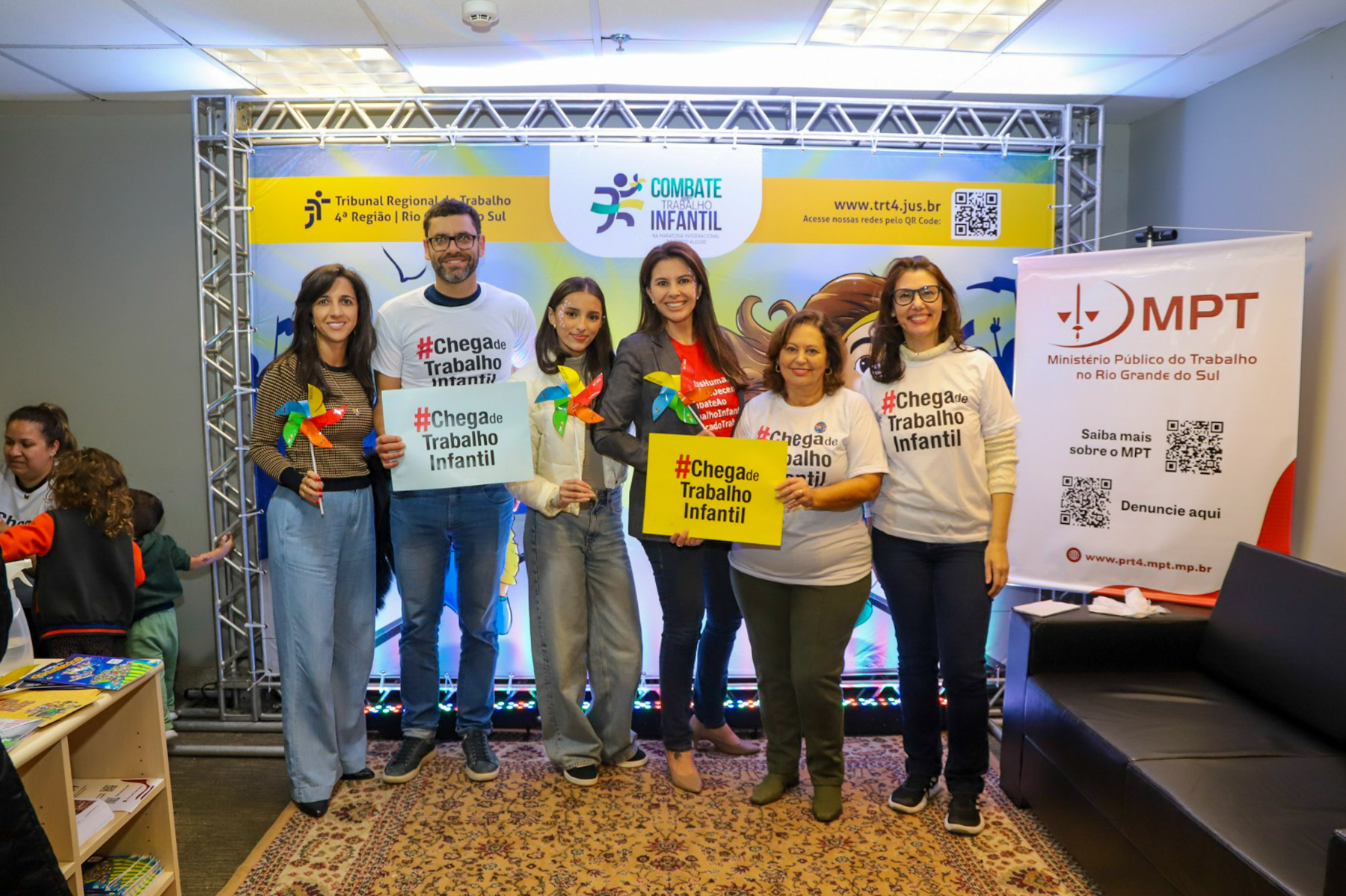 Foto posada de pessoas, no estande, segurando o cartaz #Chega de Trabalho Infantil