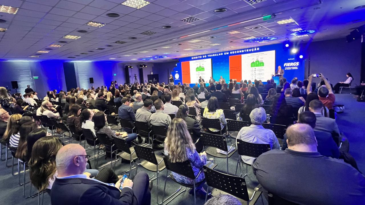 Foto em Angulo aberto, mostrando público em primeiro plano e palco ao fundo