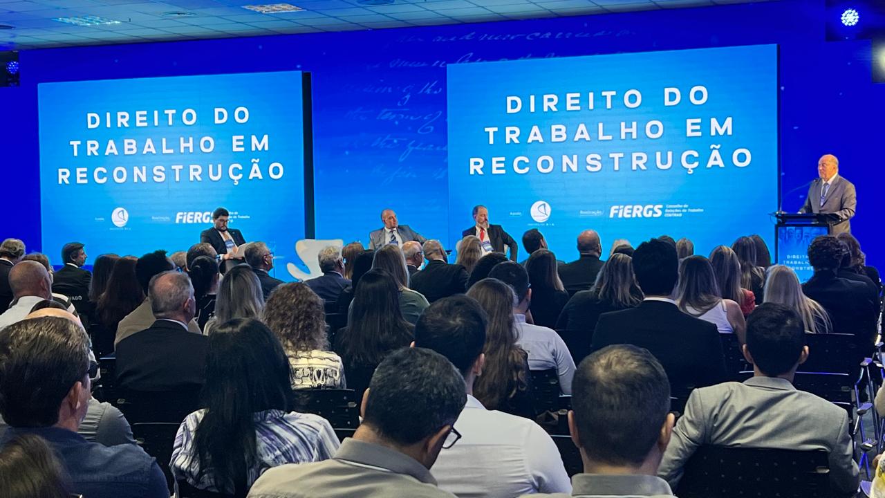 Foto mostrando público em primeiro plano e des. Martins Costa, falando no palco, ao fundo.