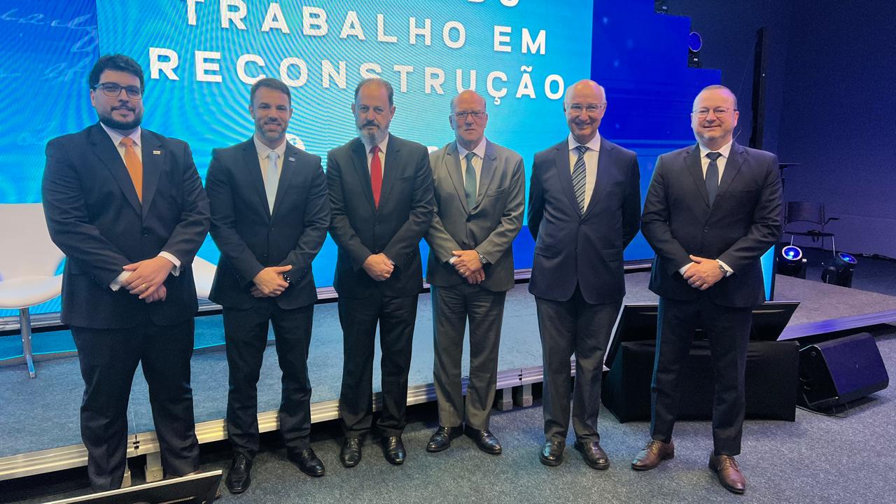 Foto posada de painelistas do evento e membros do Contrab, em pé, no palco