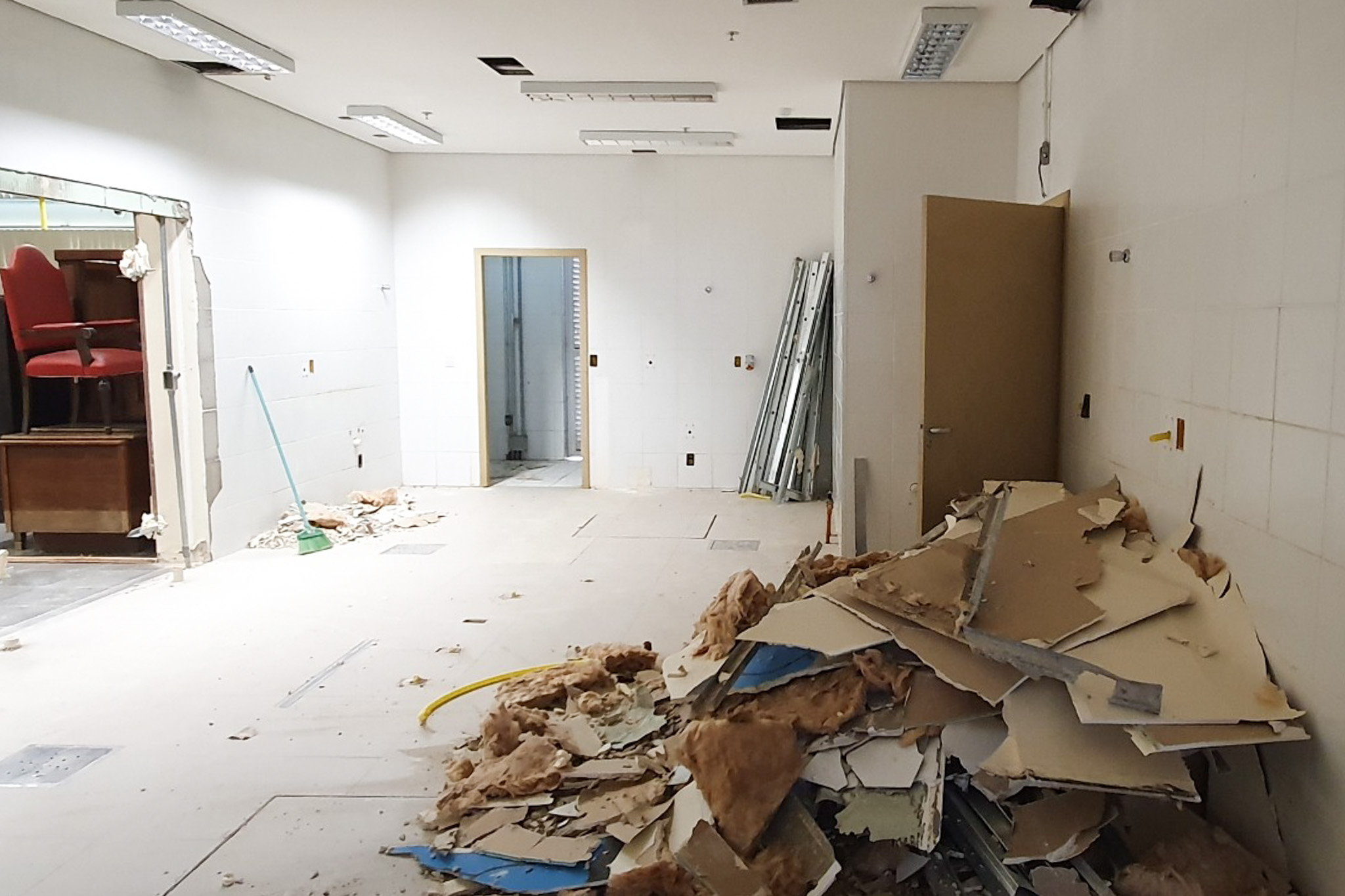 Sala em reformas, com uma pilha de entulhos no canto direito, e móveis guardados no canto esquerdo.