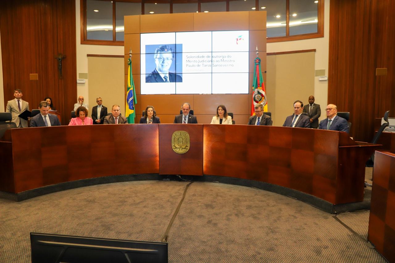 Cerimônia solene de homenagem póstuma ao ministro Paulo de Tarso Sanseverino, com autoridades reunidas no plenário e imagem do homenageado projetada ao fundo.