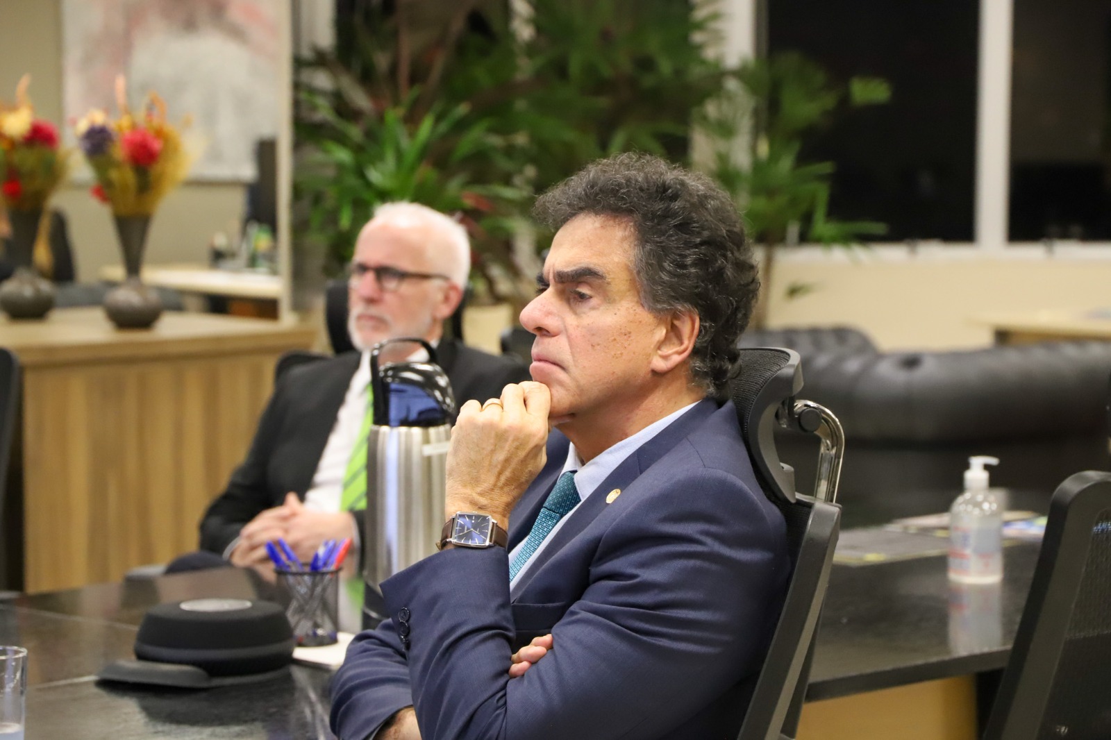 O Ministro Luiz Philippe Vieira de Mello Filho, de terno azul, com expressão concentrada e mão no queixo, observa atentamente, enquanto outro homem de cabelos brancos aparece desfocado ao fundo.
