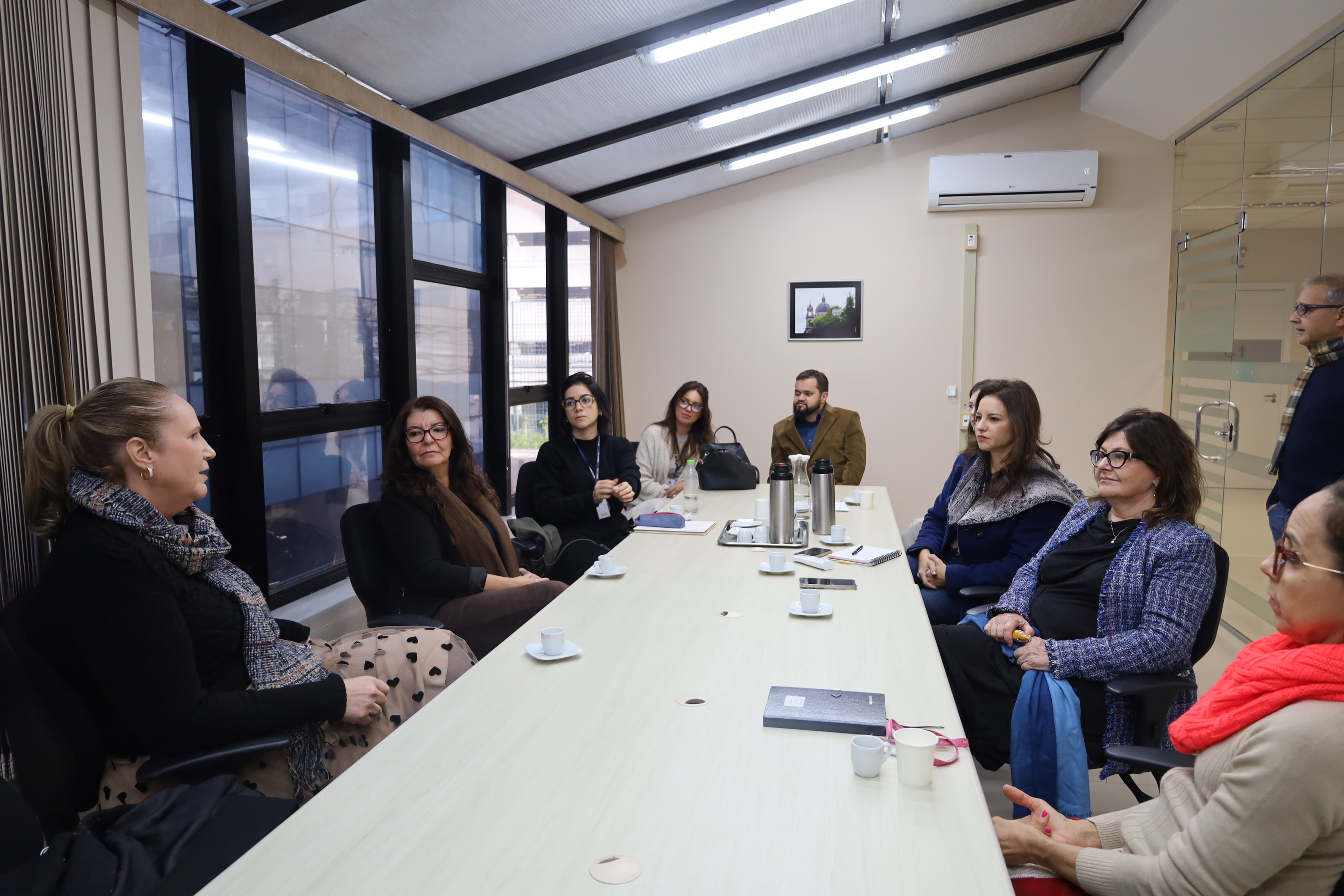 fotografia com todos os participantes da reunião, sentados em volta de uma mesa.