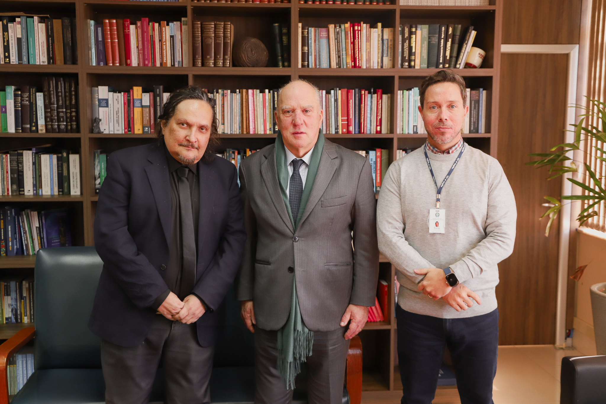 Da esquerda para a direita, Gabriel Velloso, Martins Costa e Rodrigo Trindade em frente a uma estante de livros no gabinete da Presidência.