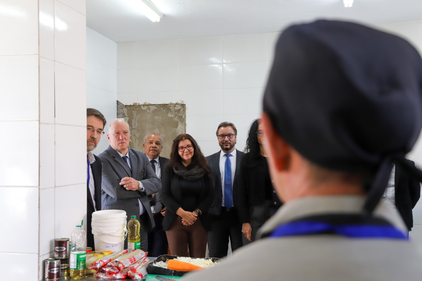 A foto mostra um recuperando apresentando a cozinha aos visitantes.