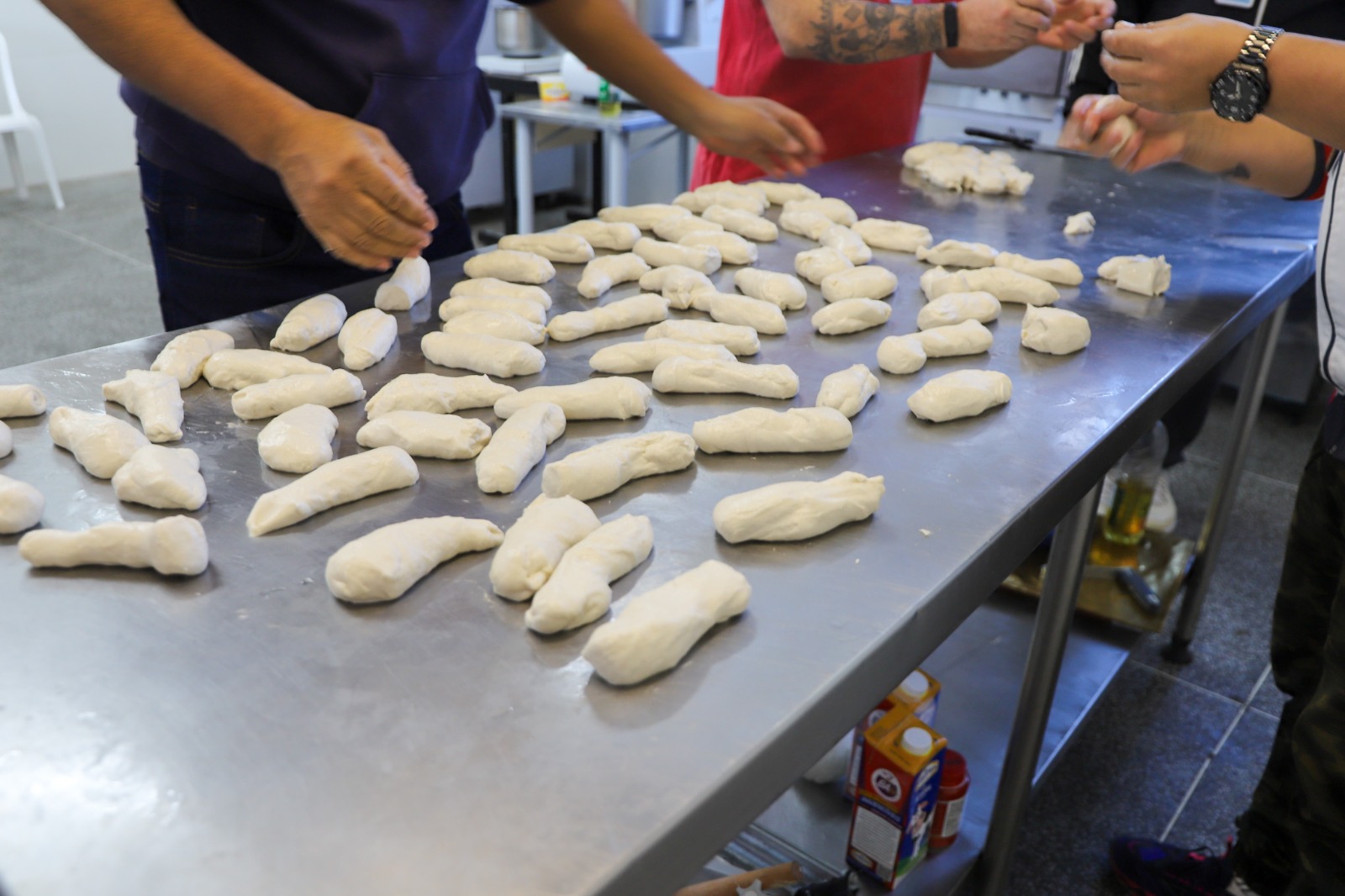 A foto mostra recuperandos produzindo pães.