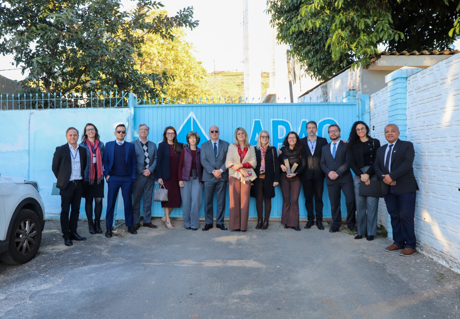A foto é posada de várias pessoas em frente à Apac.