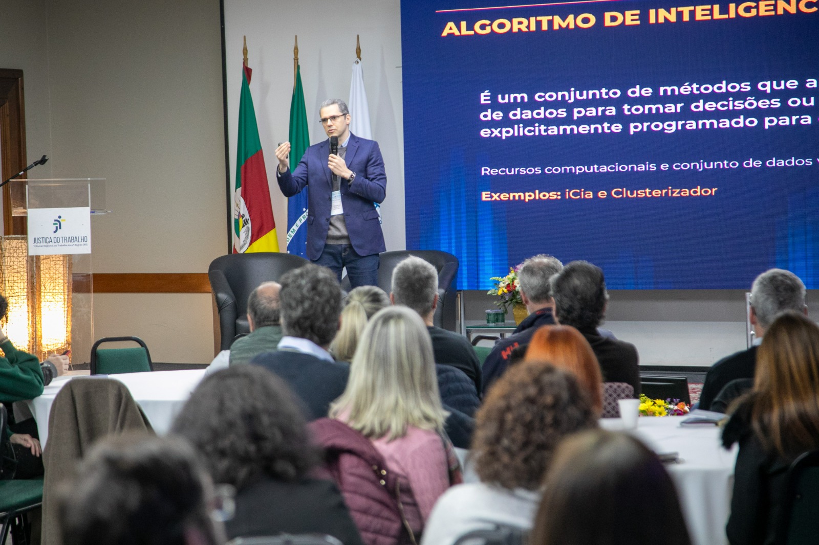 A foto mostra o servidor Frederico ao fundo e o público em primeiro plano.