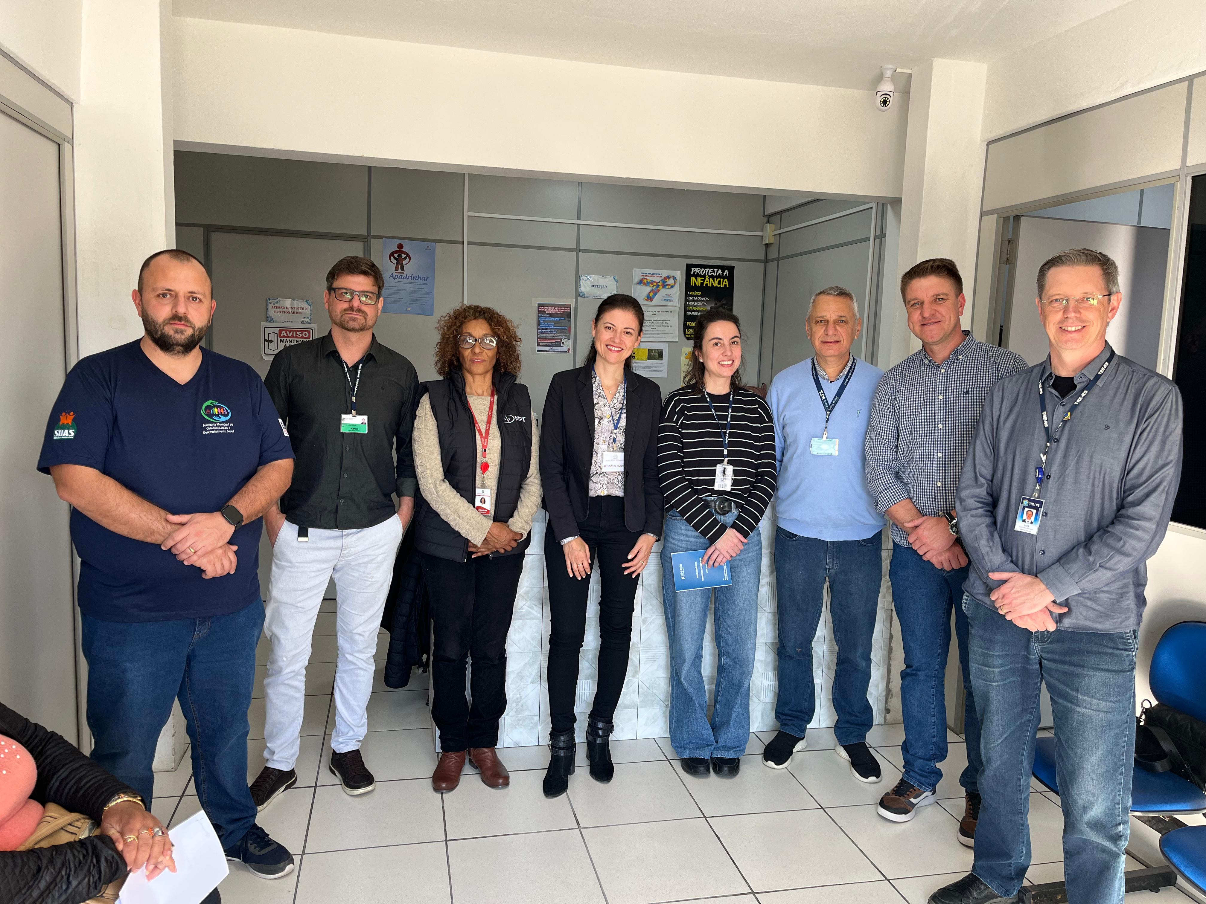 Registro de visita institucional com oito representantes de órgãos públicos em ambiente administrativo.