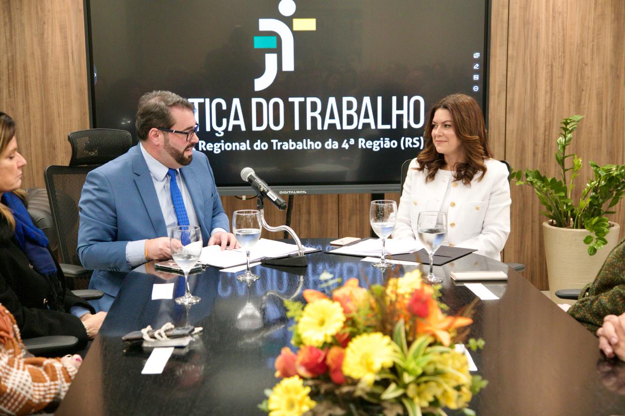 A foto mostra o desembargador Alexandre ao lado da juíza discursando.