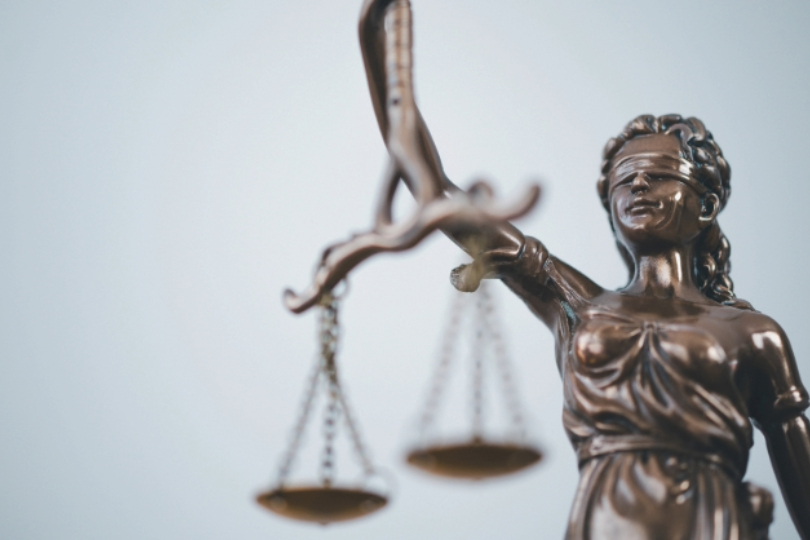Estátua Têmis, deusa graga símbolo da justiça, em metal de cor cinza.