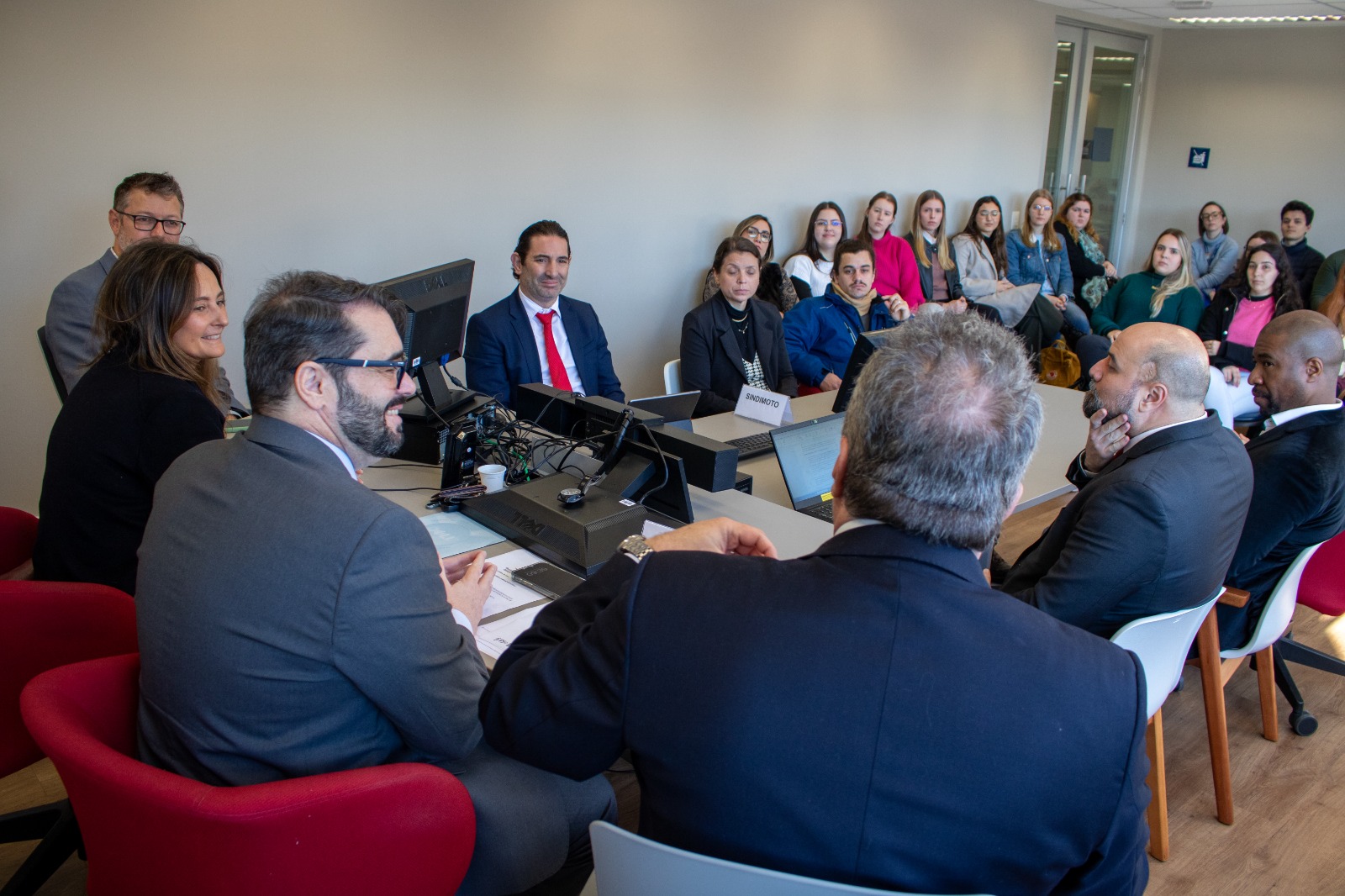 A foto mostra pessoas em volta de uma mesa de mediação, com desembargador Alexandre de costas.