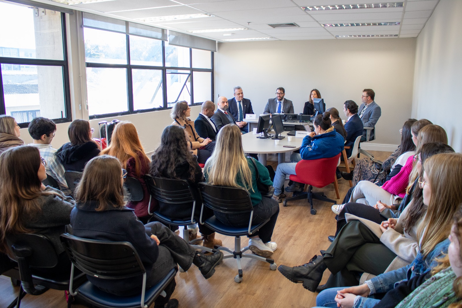 A foto mostra sessão de mediação, com pessoas em volta de uma mesa.
