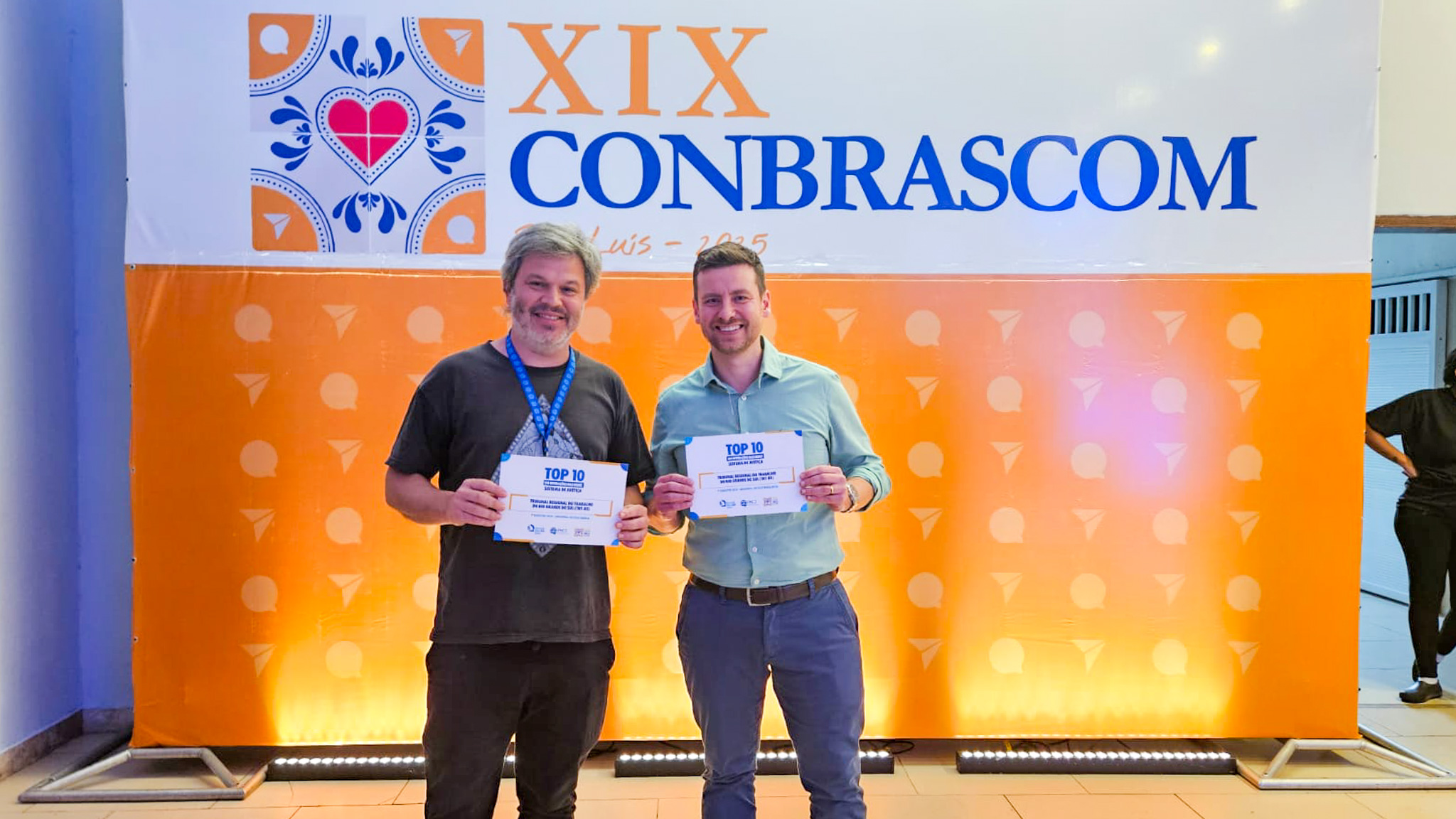 A foto mostra os servidores érico e gabriel com certificados em mãos.