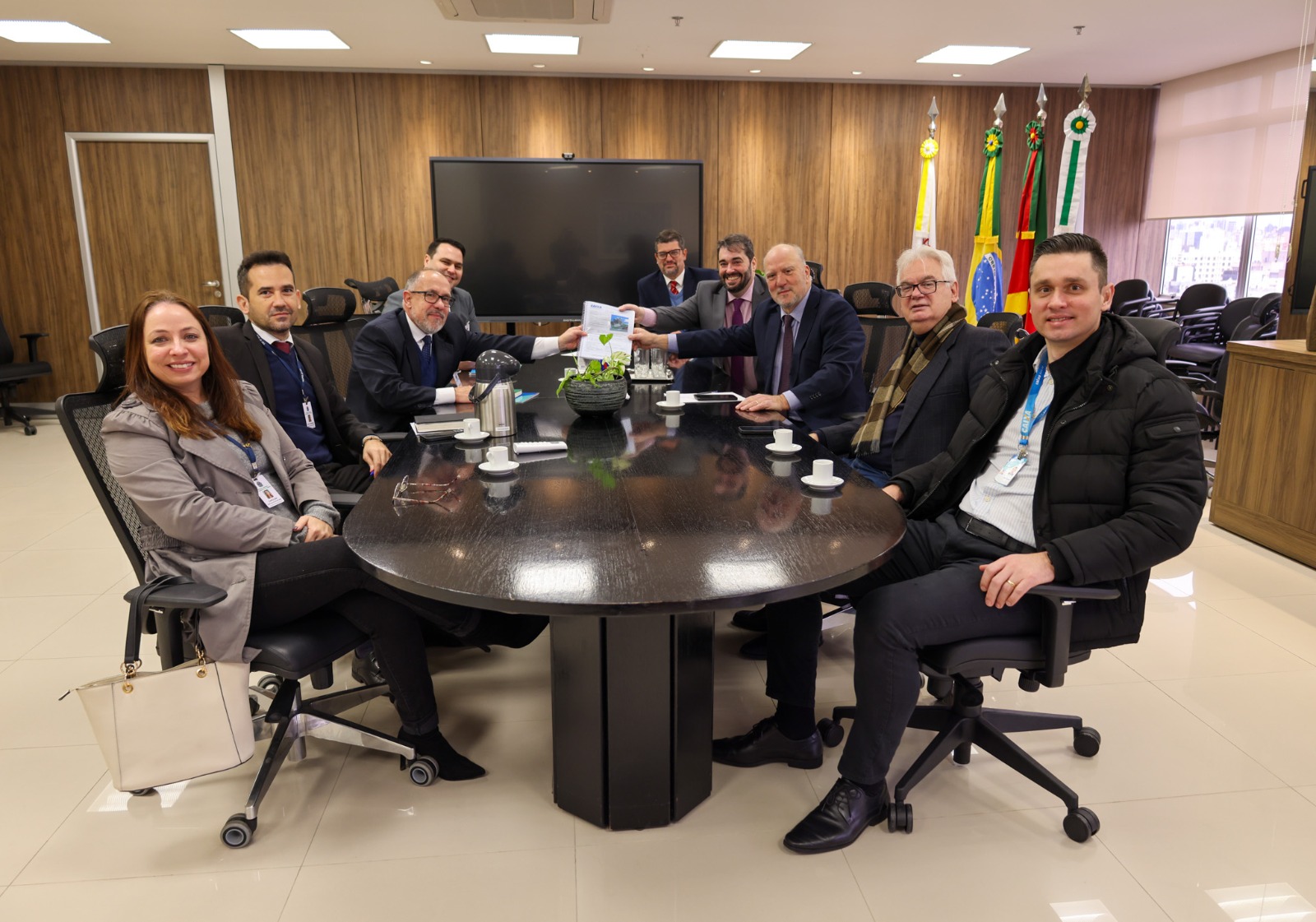 A foto posada mostra pessoas sentadas ao redor num mesa.