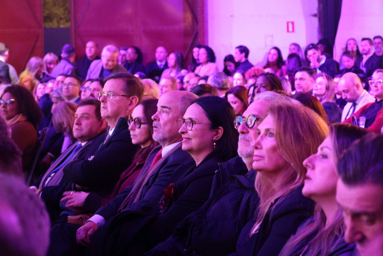 A foto mostra o público, com alguns em primeiro plano.