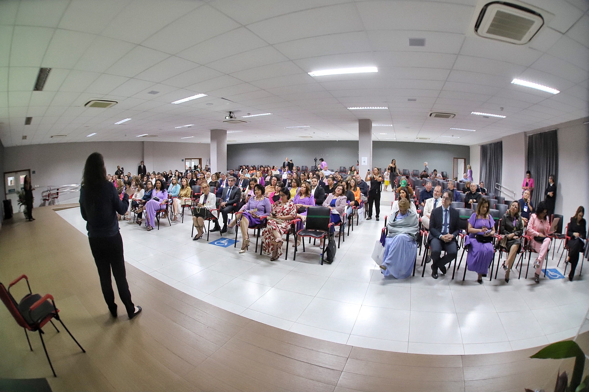 Foto em ângulo aberto, mostrando palestrante e público