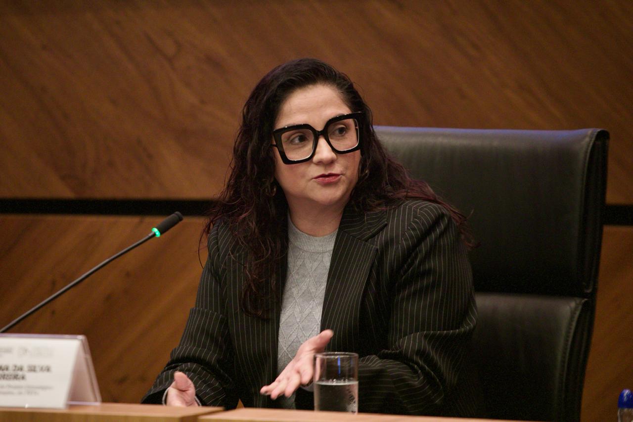 A foto mostra a servidora Carolina discursando.