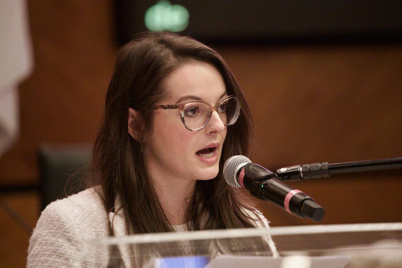 A foto mostra a servidora Lara falando ao microfone.