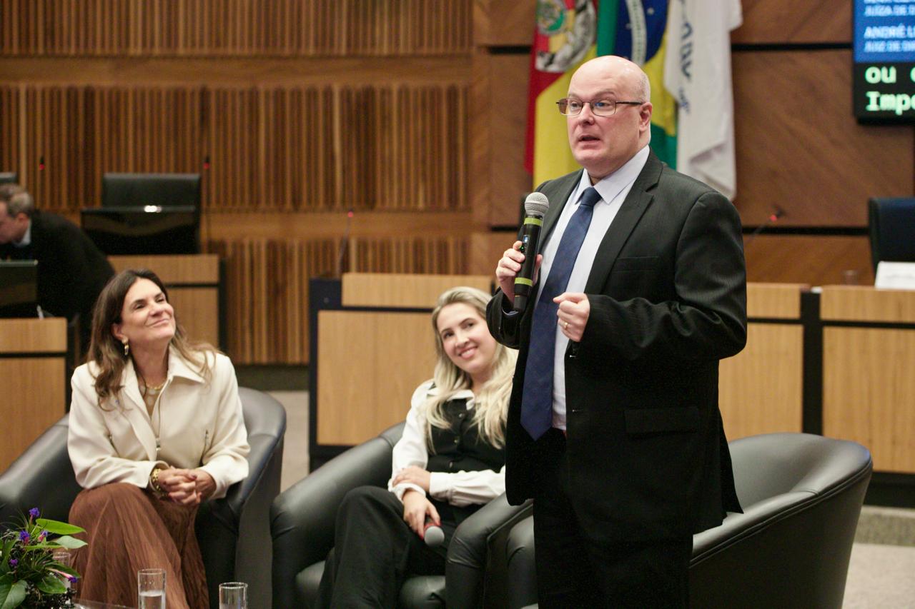 A foto mostra o juiz André palestrando em pé.