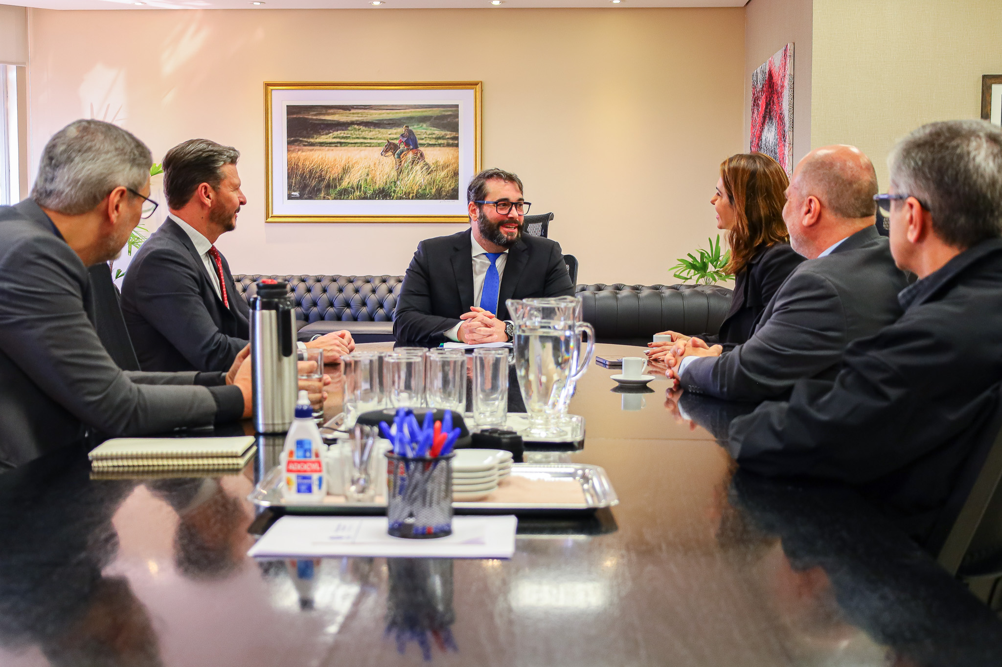 Foto da reunião no Salão Nobre, mostrando os participantes sentados à mesa, conversando.