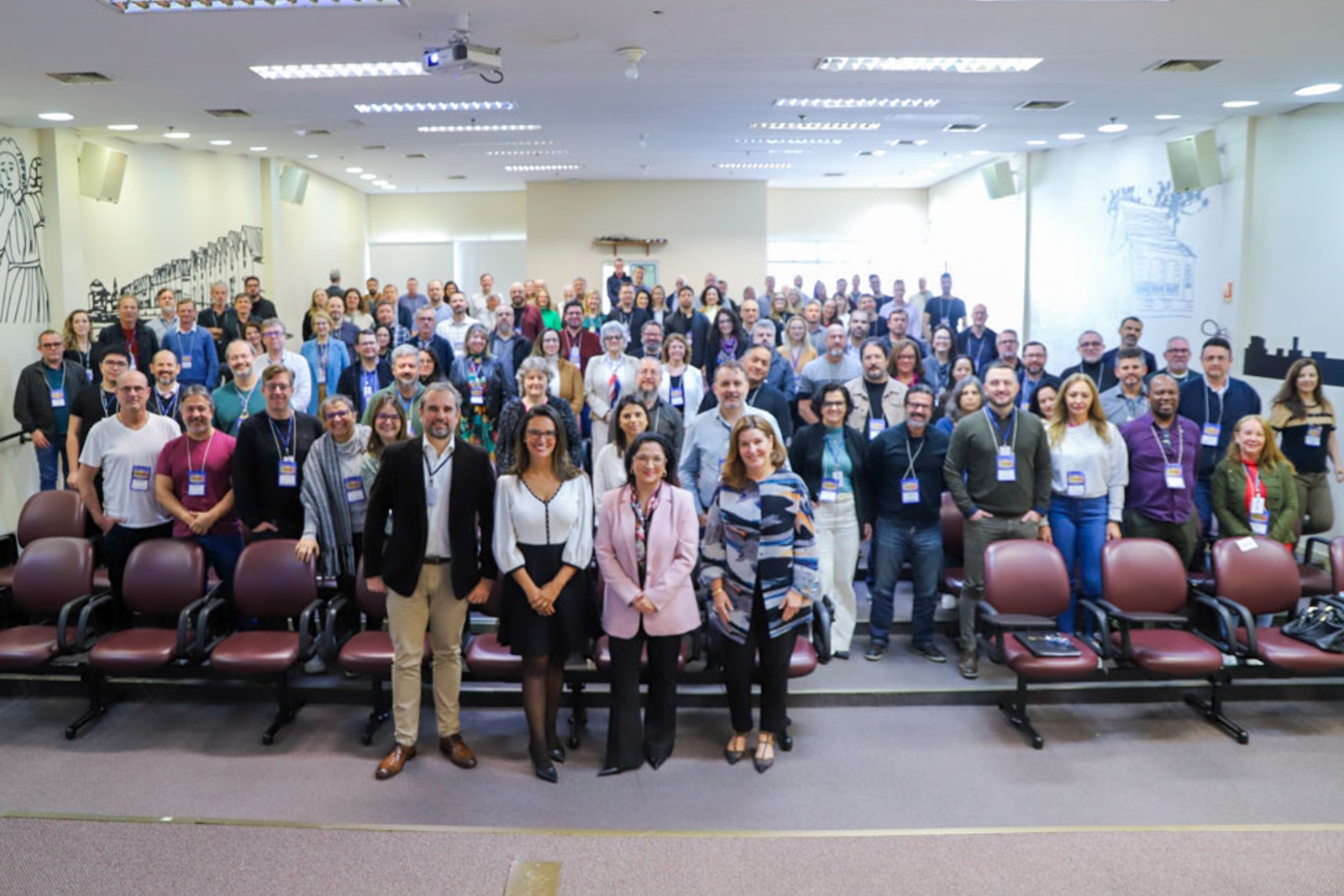 Diversas pessoas na plateia de pé posando para  a foto.
